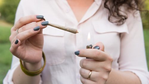 Women with a cannabis joint and lighter in hand
